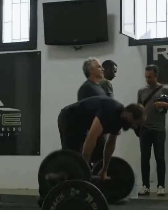 Le coach avec deux haltères devant le mur au logo ELITE